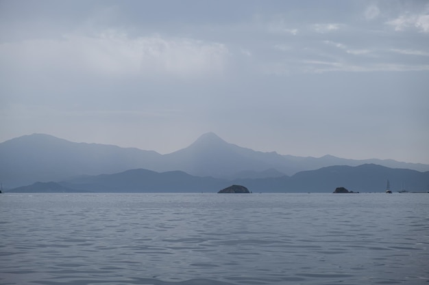 Blick auf Meer und Berge Silhouette in bewölktem Nebel Tag friedliche nordische Landschaft