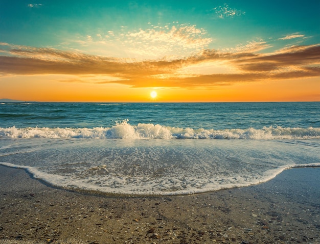 Foto blick auf meerwasserschaum am strand bei dramatischem sonnenuntergang