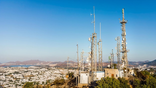 Blick auf Telekommunikationsmast-TV-Antennen bei Sonnenaufgang auf dem Berg mit Antenne im Hintergrund der Stadt