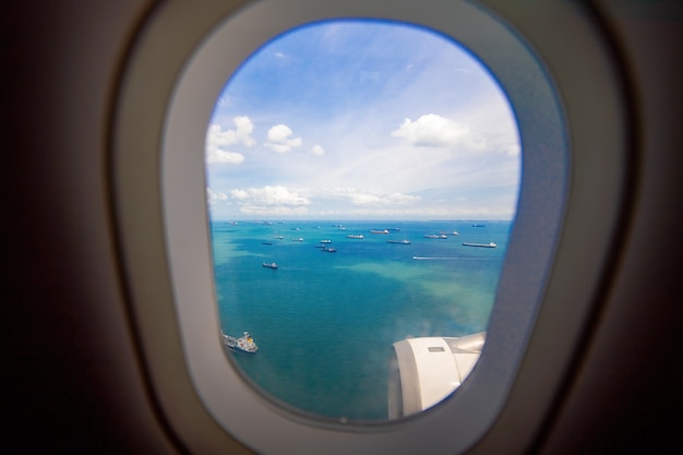 Blick aus dem Fenster des Flugzeugs auf See- und Frachtschiffe sorgloser Blick aus dem Bullauge Landungsflugzeug