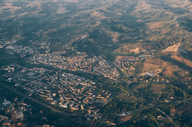 Blick aus dem Flugzeugfenster auf die grünen Bergketten und die Stadt in der Toskana