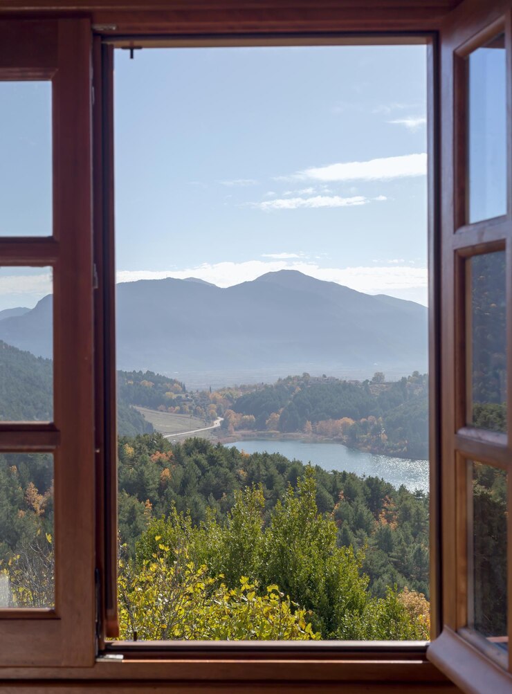 Blick aus dem offenen Fenster auf den See und die Berge an einem sonnigen Herbsttag