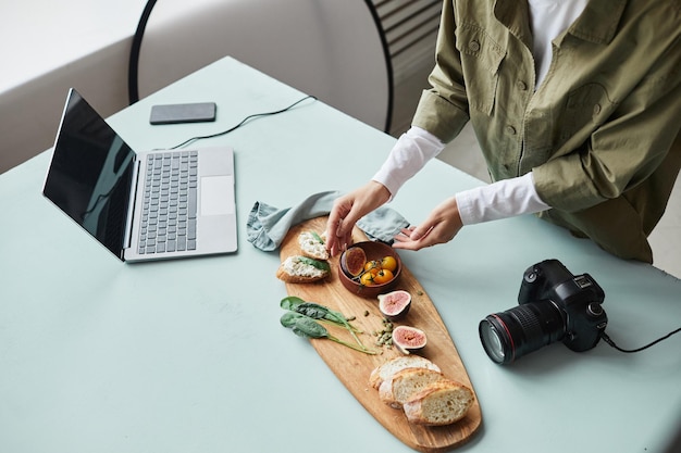 Blick aus der Vogelperspektive auf eine Food-Fotografin, die Gourmetgerichte mit Requisiten arrangiert, während sie im Studiokopierraum arbeitet