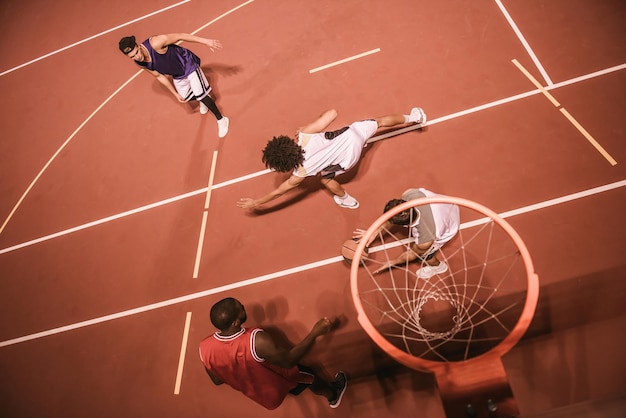 Blick aus der Vogelperspektive auf gutaussehende Jungs, die nachts im Freien Basketball spielen