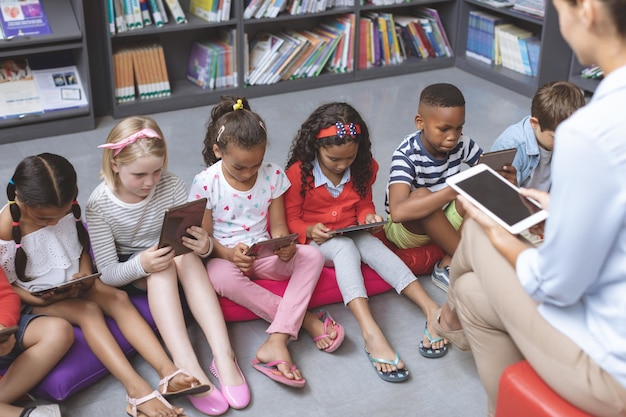 Blick aus der Vogelperspektive auf Schulkinder, die wie ihr Lehrer ein digitales Tablet halten