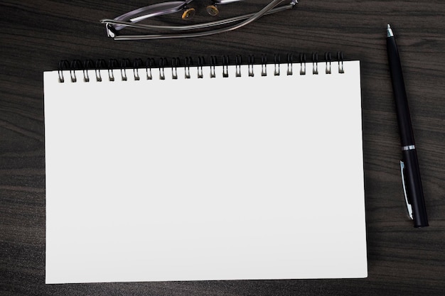 Foto blick direkt über dem bürotisch aus holz mit stift-notepad und leseglas flach gelegter kopierplatz