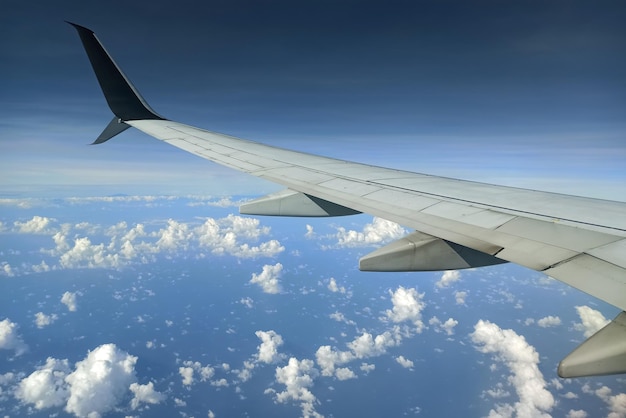 Blick durch das Flugzeugfenster des Verkehrsflugzeugflügels, der hoch in den Himmel fliegt Luftreisekonzept