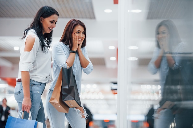 Blick durch das Glas. Zwei junge Frauen verbringen gemeinsam einen Einkaufstag im Supermarkt.