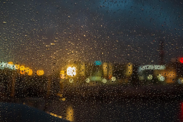 Blick durch nasses Glas auf die nächtlichen Lichter der Böschung