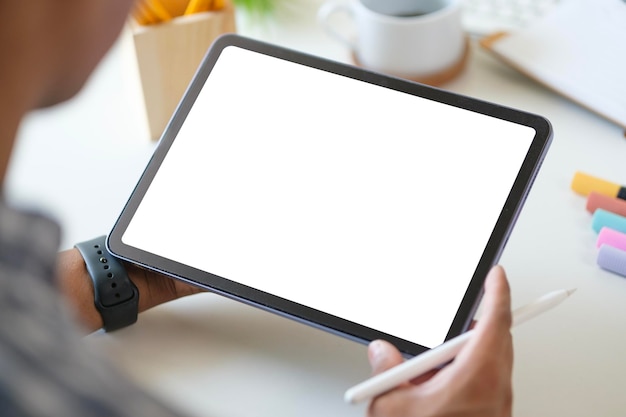 Blick über die Schulterhände eines Geschäftsmannes mit digitalem Tablet am weißen Schreibtisch