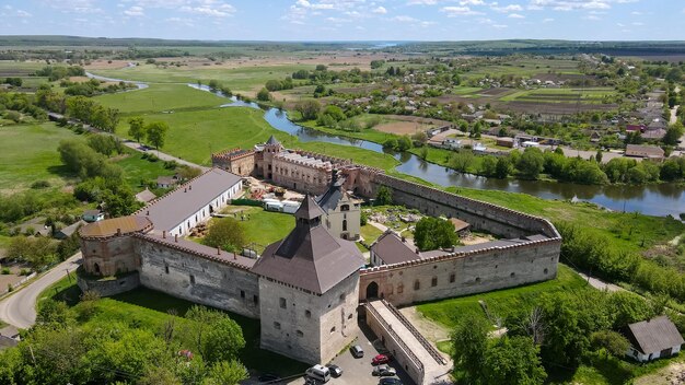 Blick von einer Höhe auf eine mittelalterliche Burg am Ufer des Flusses. Medzhybizh-Festung