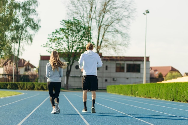 Blick von hinten auf ein Sportpaar, das morgens im Stadion läuft Training Running