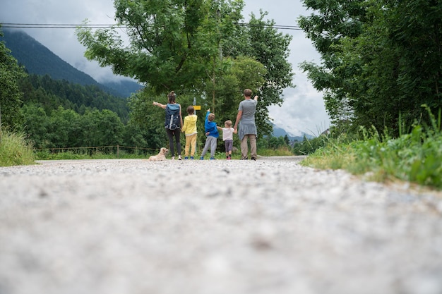 Blick von hinten auf eine fünfköpfige Familie, die an einer Kreuzung von Wanderwegen steht und jedes Familienmitglied in eine Richtung zeigt, in die es gehen möchte