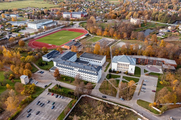 Blick von oben auf das Gymnasium Dobele und den Sportplatz im Hintergrund Dobele Lettland