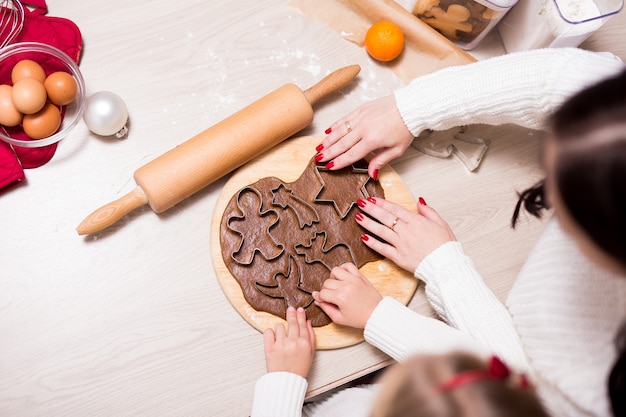 Blick von oben auf das kleine Mädchen und ihre Mutter, die Weihnachtsplätzchen oder Lebkuchen in der Küche kochen