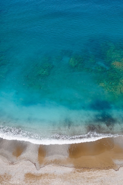 Blick von oben auf das Meer mit azurblauem Wasser und einem Sandstrand. Luftaufnahme des Mittelerdemeeres mit Küstenlinie. Schönes tropisches Meer in der Sommersaison, geschossen von der Drohne