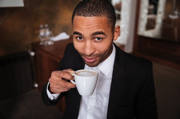 Blick von oben auf den afrikanischen Mann im Anzug, der Kaffee im Hotel trinkt