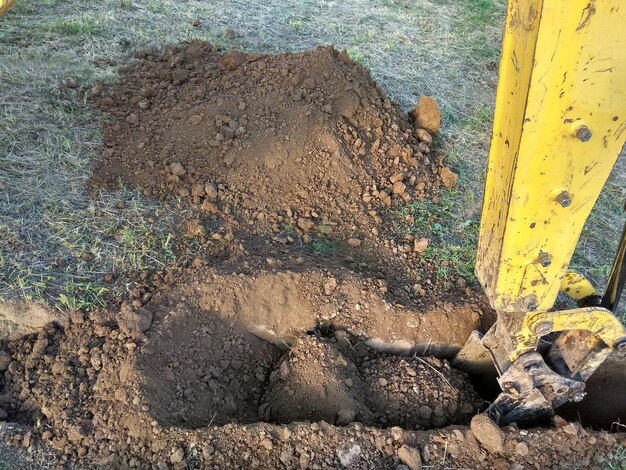 Blick von oben auf den arbeitenden Baggertraktor, der einen Graben aushebt