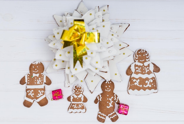 Blick von oben auf den entzückenden hausgemachten Lebkuchen-Weihnachtsbaum mit süßer Lebkuchenfamilie mit Geschenken auf weißem Holzschreibtisch