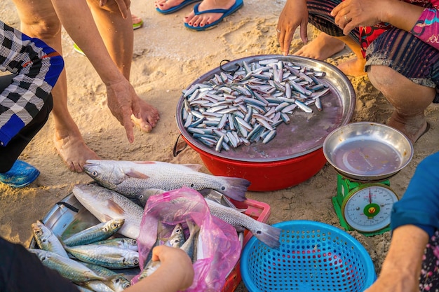 Blick von oben auf den Fischer, der Fisch am Strand verkauft, nachdem er so viele Tage vom Meer zurückgekehrt ist und am Boot gearbeitet hat Traditionelle Fischer