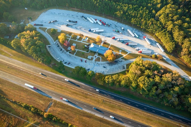 Blick von oben auf den großen Rastplatz in der Nähe der belebten mehrspurigen amerikanischen Autobahn mit schnell fahrenden Autos und Lastwagen