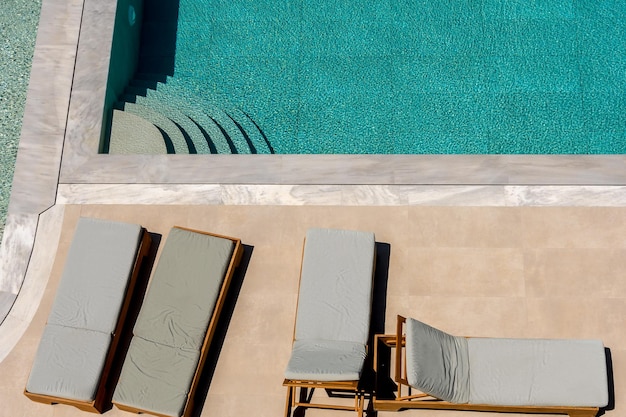 Blick von oben auf den Swimmingpool mit Sonnenliegen. Sommerlicher Hintergrund