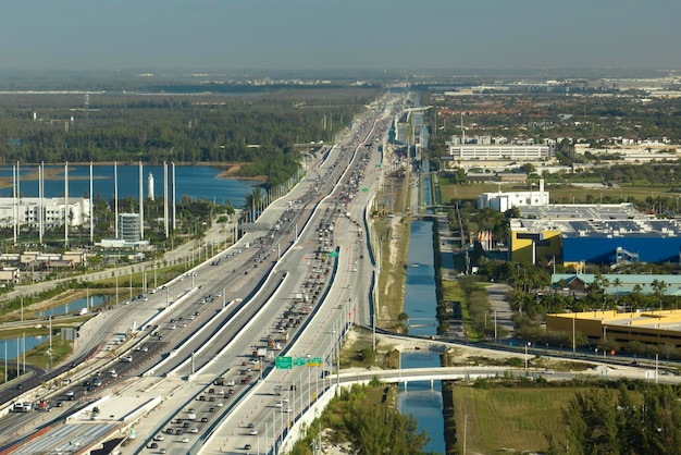 Blick von oben auf die amerikanisch breite Autobahn in Miami, Florida, mit dichtem Verkehr fahrender Autos während der Hauptverkehrszeit. Verkehrsinfrastrukturkonzept der USA