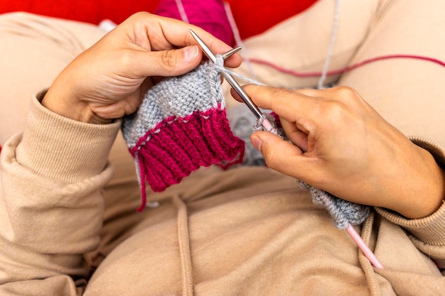 Blick von oben auf die Hände einer Frau, die mit Nadeln und Wolle stricken