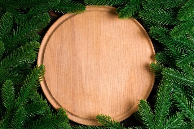 Blick von oben auf die Holzplatte, die mit Tannenzweigen verziert ist. Silvester-Dinner-Konzept mit leerem Raum für Ihr Design.