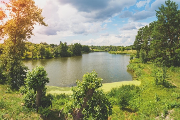 Blick von oben auf die Landschaft und den Fluss an einem sonnigen Tag. Naturlandschaft mit einem wunderschönen bewölkten Himmel. Sommerzeit