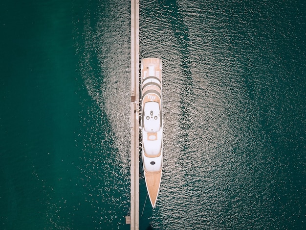 Blick von oben auf die luxuriösen weißen Yachten, die an einem sonnigen Tag am langen, dünnen Kai, blaues Meer vor Anker liegen; Millionär Konzept.