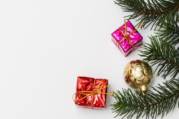 Blick von oben auf die roten Kugeln der Weihnachtsgeschenkbox mit Fichtenzweigen, Tannenzapfen, roten Beeren und Glocke auf weißem Hintergrund