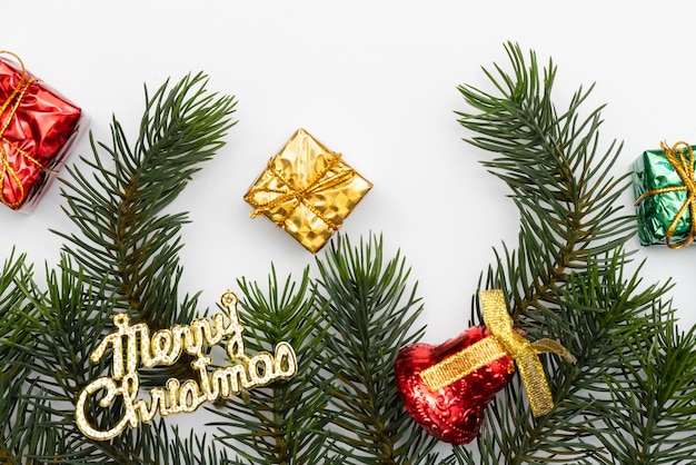 Blick von oben auf die roten Kugeln der Weihnachtsgeschenkbox mit Fichtenzweigen, Tannenzapfen, roten Beeren und Glocke auf weißem Hintergrund