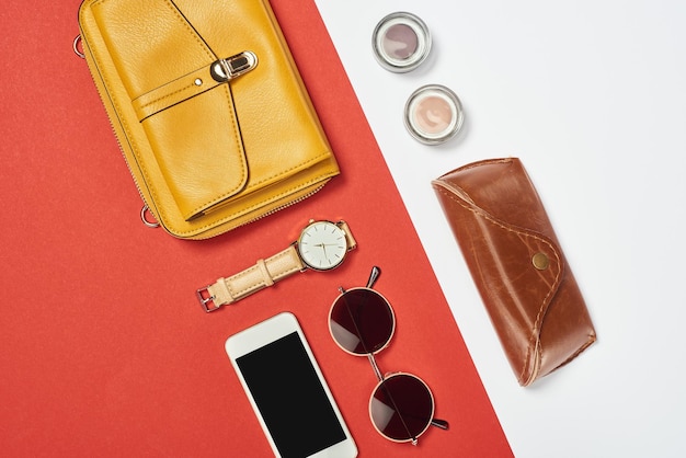 Blick von oben auf die Tasche, Sonnenbrille, Lidschatten, Smartphone-Uhr und -Hülle