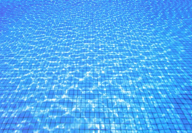 Blick von oben auf die Wellen des blauen Wassers im Schwimmbad. Sommerhintergrund mit Kopienraum