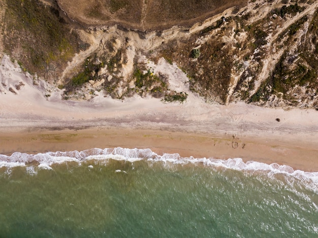 Blick von oben auf die Wellen, die im Sand brechen und über tropischen Sandstrand und Wellen fliegen