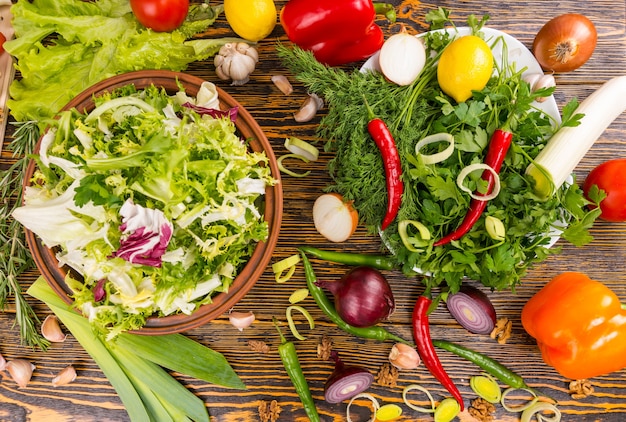 Blick von oben auf Rosmarin, Salat, Lauch, Zwiebel, Paprika, Zitrone und andere köstliche Zutaten auf Holztisch