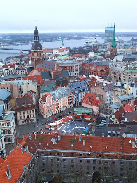 Blick von oben auf Ziegeldächer, Straßen mit Menschen und geparkten Autos. Riga, Lettland