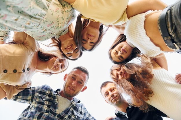 Blick von unten auf junge positive Menschen, die nach unten schauen