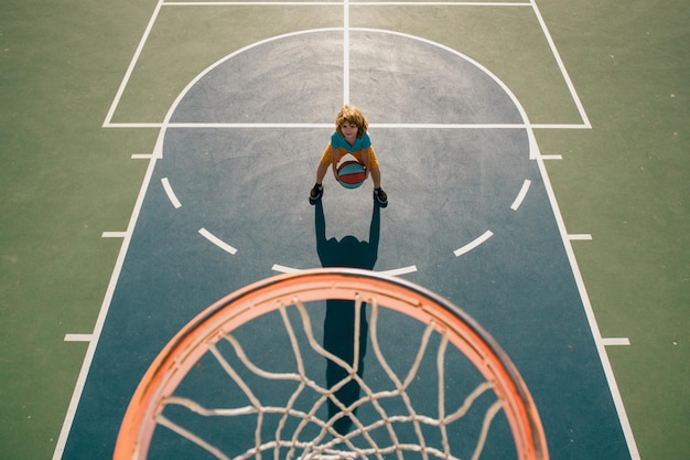 Blickwinkel von oben auf das Kind, das Basketball auf dem Spielplatz spielt