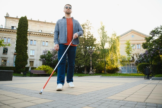 Blinder Mann, der auf Bürgersteig mit Stock geht