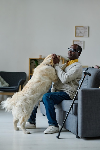 Blinder Mann mit Blindenhund, der zu Hause sitzt