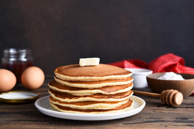 Blini o panqueques apilados en una mesa de madera con mantequilla Maslenitsa concepto de vacaciones Desayuno de estilo rústico