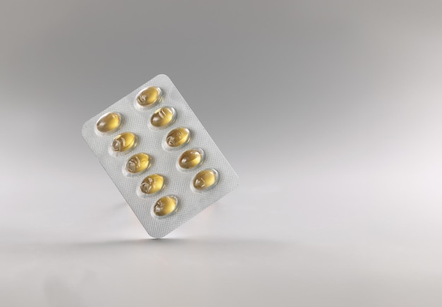 Blister com comprimidos amarelos de gelatina óleo de peixe dose diária de medicamentos para pessoa comprimidos em embalagem de plástico