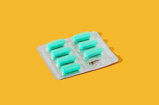 Blíster con pastillas de color turquesa sobre un fondo amarillo