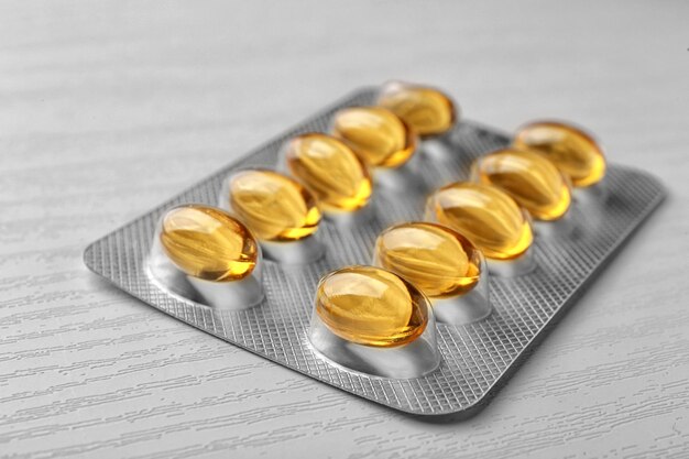 Blisterpackung mit Lebertran-Kapseln auf weißem Holzhintergrund