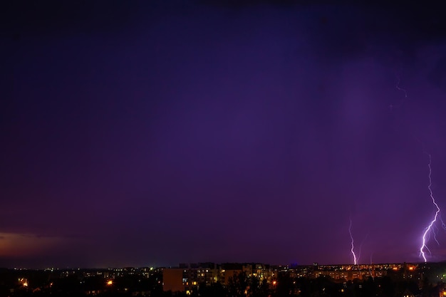 Blitz schlägt Sturm über dem lila Licht der Stadt ein.