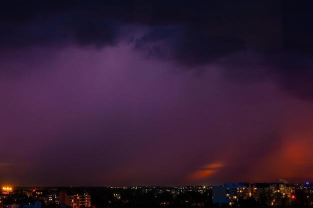 Blitz schlägt Sturm über dem lila Licht der Stadt ein.