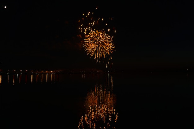 Blitze von festlichem Feuerwerk über dem Nachtfluss spiegeln sich im Wasser