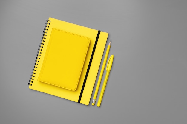 Bloc de notas amarillo con lápiz amarillo sobre fondo gris cerrar